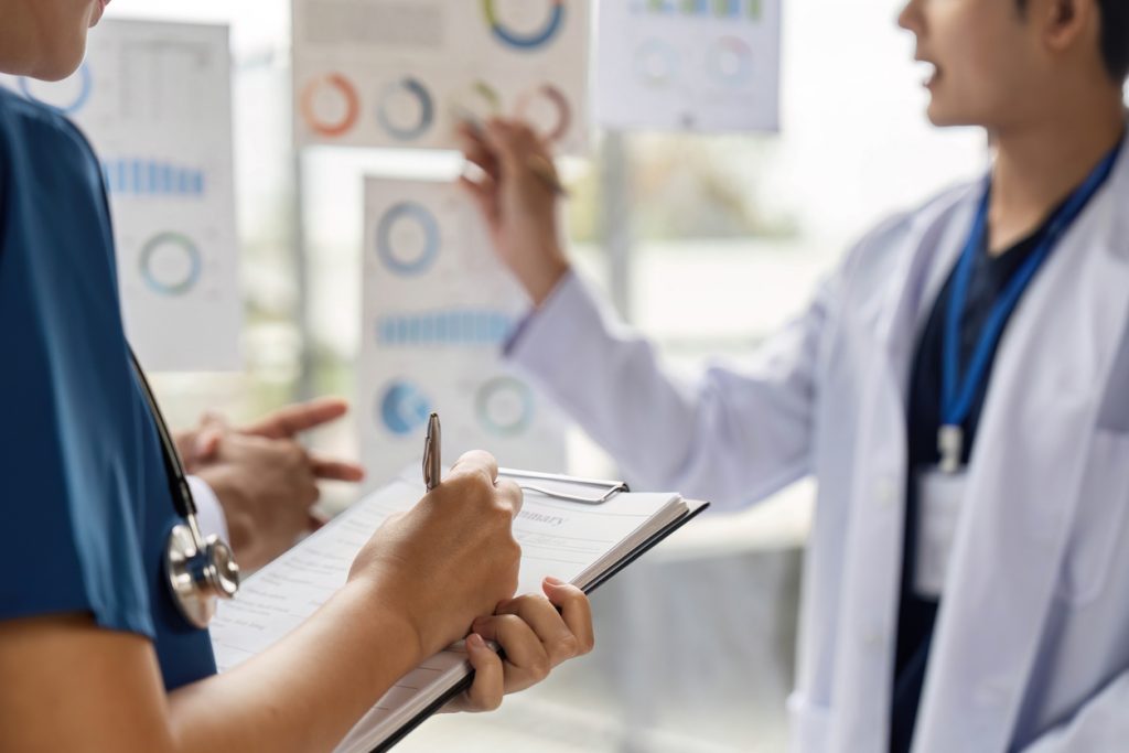 A group of doctors analyzing charts and discussing patient data in a collaborative medical environment, showcasing teamwork and patient care.