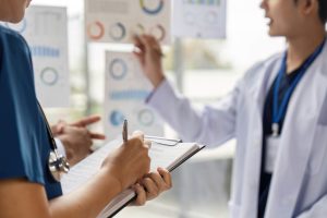 A group of doctors analyzing charts and discussing patient data in a collaborative medical environment, showcasing teamwork and patient care.