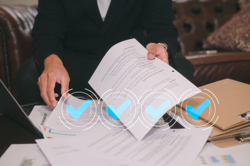 Man sitting in office or sofa in living room analyse paper report data and virtual correct marks, using laptop for work or study data analysis in business or research on data charts