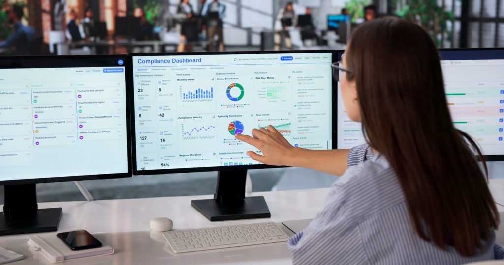 Woman Analyzes Real-time Risk Dashboard On Multiple Screens For Strategic Decisions.